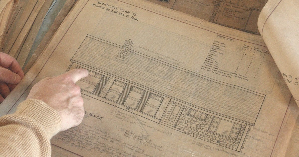 Photograph showing a hand pointing at a detail on an architectural drawing for a bungalow