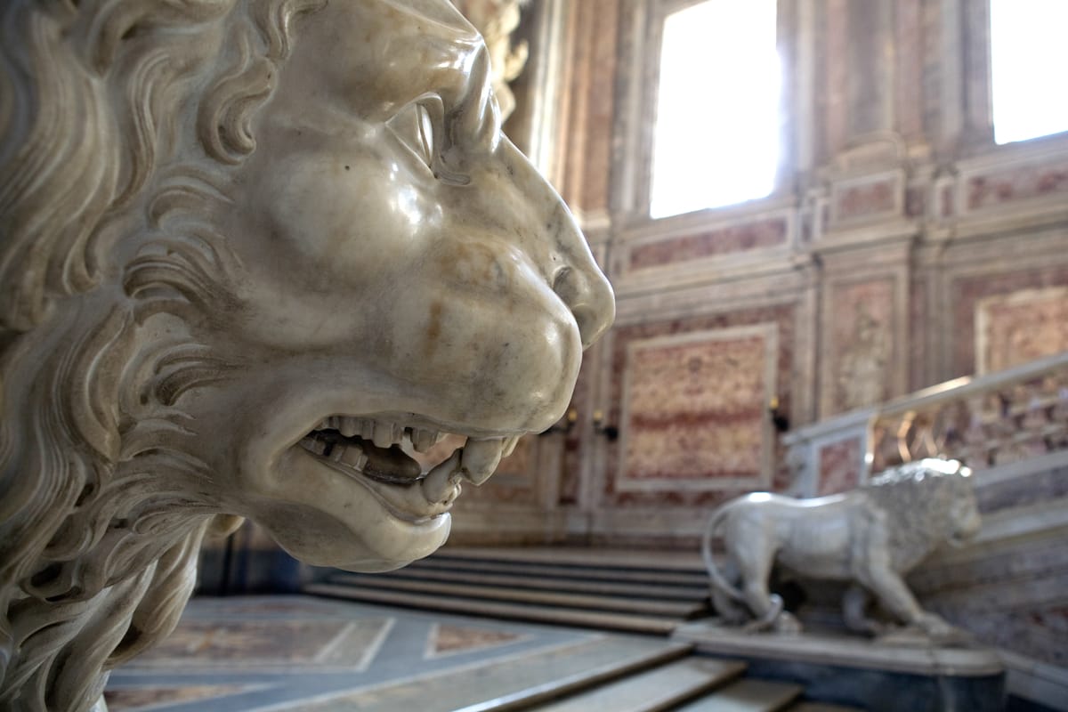 Colour photograph showing carved lion sculptures at bottom of stairs in the Royal Palace of Caserta in Italy.