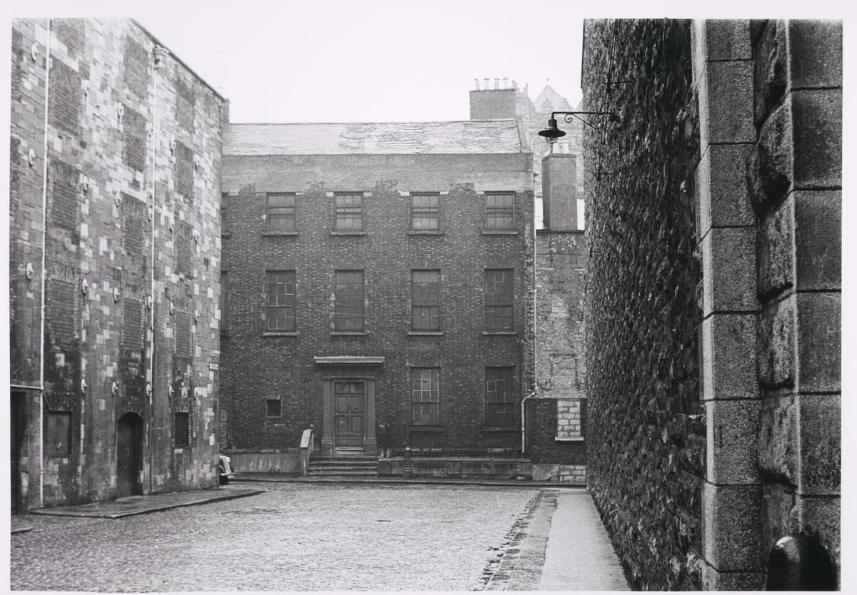 Photograph of Bow Street, Dublin, taken by Paddy Healy in 1966. In this view from New Church Street to Bow Street, the Jameson Distillery building on the left and St Michan’s Church, the tower of which is just visible, are the only survivors.